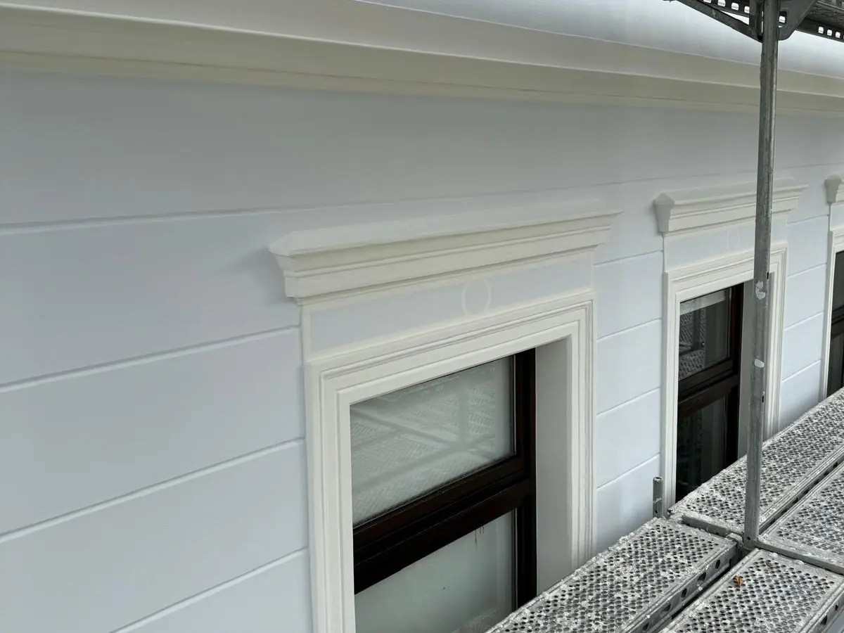Detail: frisch gestrichene Fassade mit Fensterfaschen und Verdachung in Altweiß